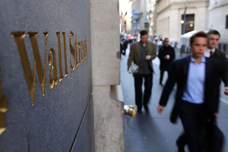 People walk along Wall Street in the financial district in New York City. (Photo by Spencer Platt/Getty Images)